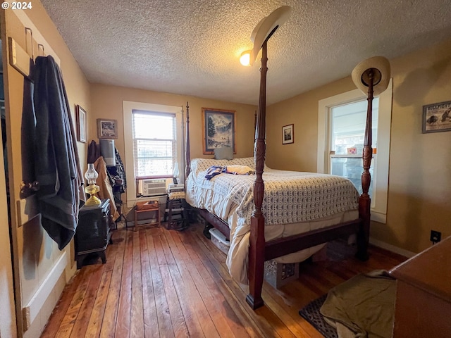 bedroom with cooling unit, a textured ceiling, and hardwood / wood-style floors