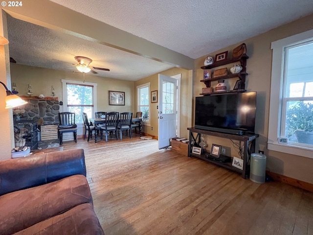 living room featuring a ceiling fan, baseboards, a textured ceiling, and hardwood / wood-style floors