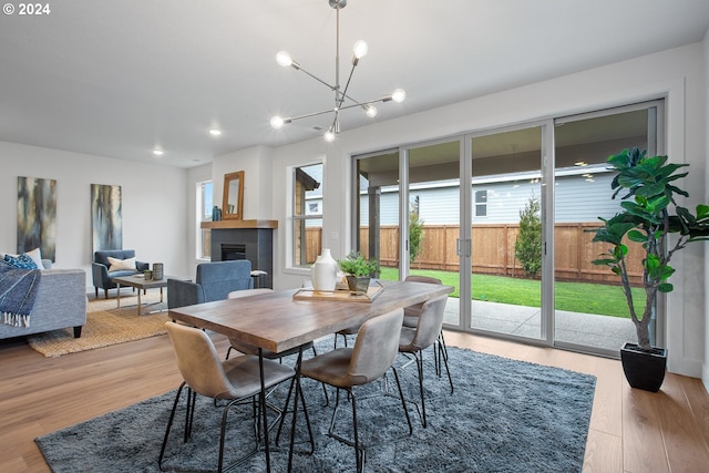 dining area featuring a fireplace, hardwood / wood-style floors, and a notable chandelier