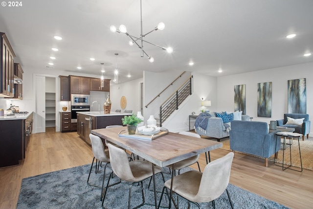 dining room featuring an inviting chandelier, light wood-type flooring, and sink