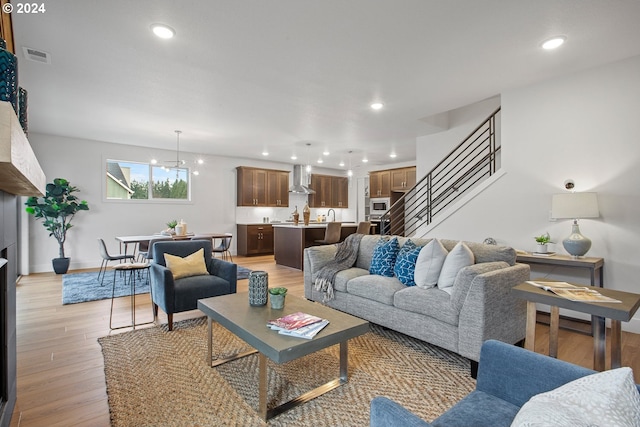 living room with light wood-type flooring and an inviting chandelier