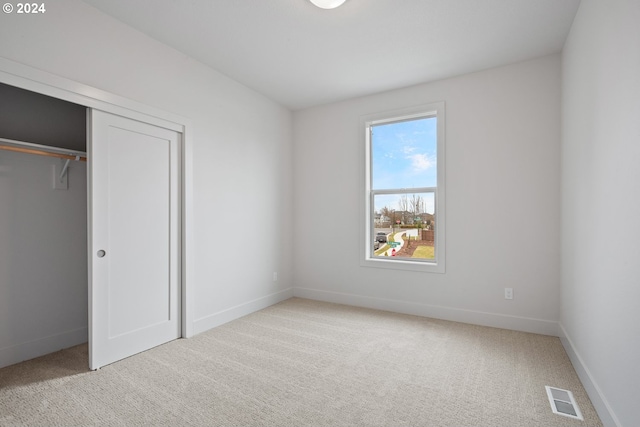 unfurnished bedroom featuring light colored carpet and a closet