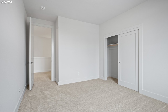 unfurnished bedroom with light carpet and a closet