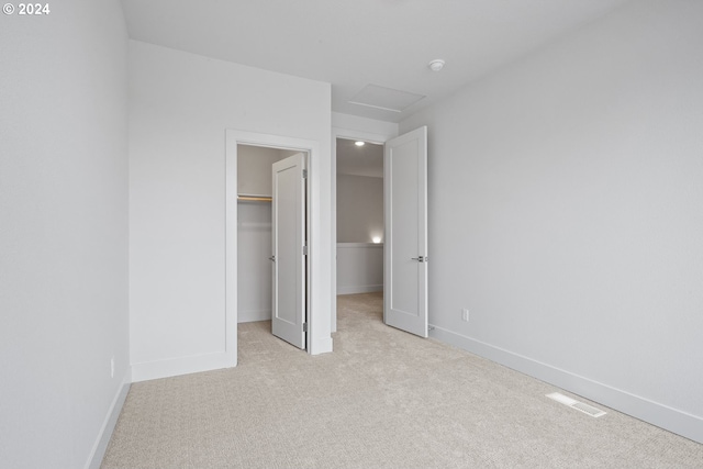 unfurnished bedroom featuring light carpet, a closet, and a walk in closet