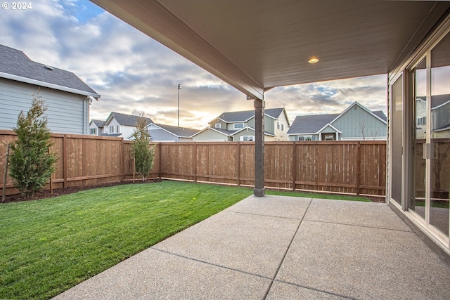 patio terrace at dusk featuring a lawn