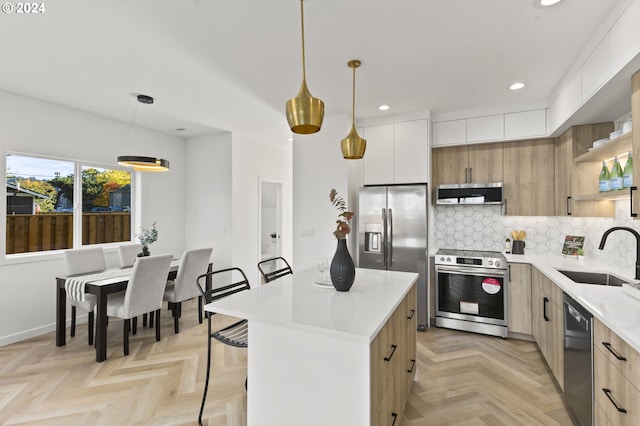 kitchen featuring appliances with stainless steel finishes, a center island, decorative light fixtures, and sink