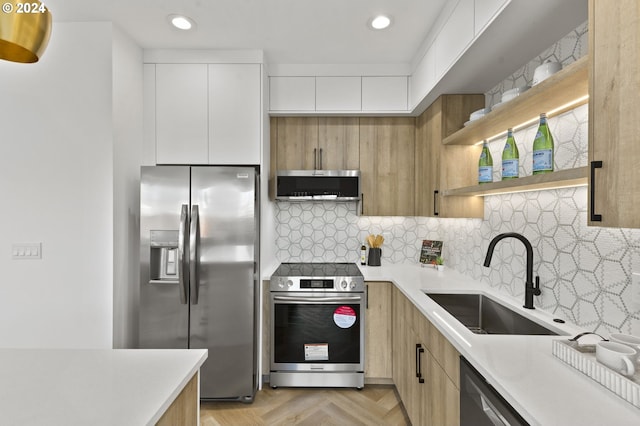 kitchen with tasteful backsplash, stainless steel appliances, sink, light parquet flooring, and white cabinetry