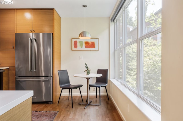 kitchen featuring decorative light fixtures, high end refrigerator, light wood-style flooring, and light countertops