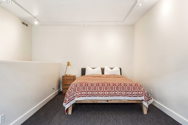 carpeted bedroom with visible vents, baseboards, and rail lighting