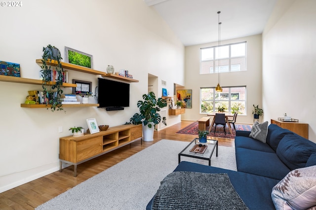 living area featuring a towering ceiling, baseboards, and wood finished floors