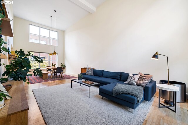 living room with baseboards, high vaulted ceiling, light wood-style flooring, beamed ceiling, and a chandelier