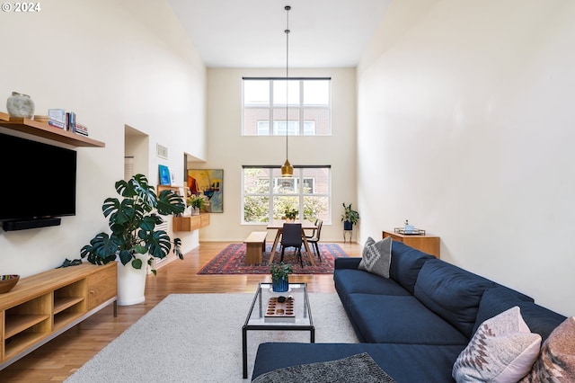 living area featuring visible vents, baseboards, a towering ceiling, and wood finished floors