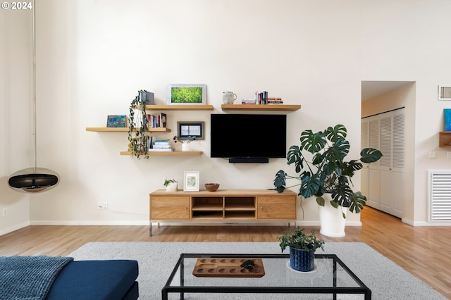 living room featuring visible vents, baseboards, and wood finished floors