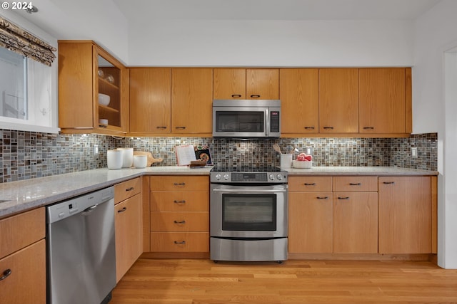 kitchen with light wood-type flooring, stainless steel appliances, and backsplash