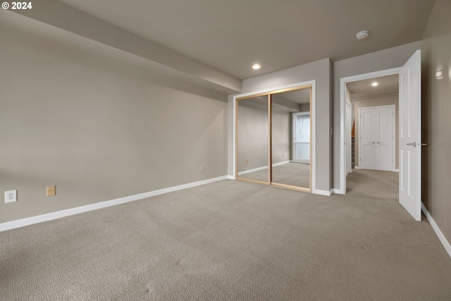 unfurnished bedroom with a closet and light colored carpet