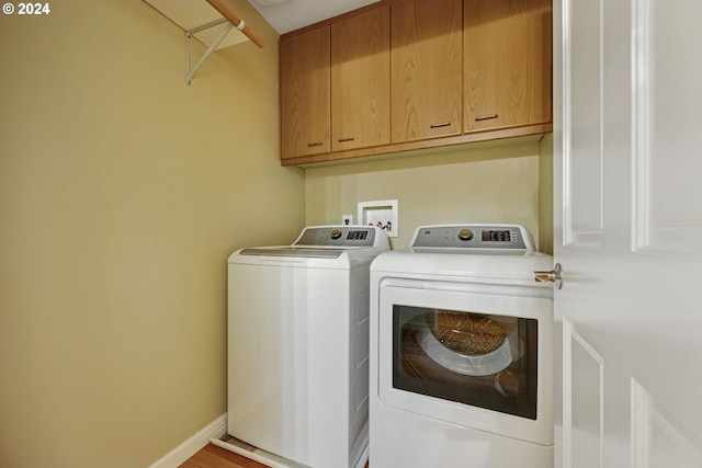 laundry room featuring washing machine and dryer, cabinets, and light hardwood / wood-style floors