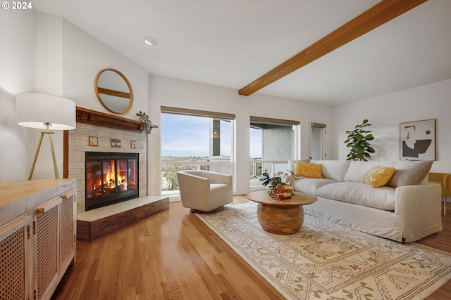 living room featuring a fireplace, beam ceiling, and light hardwood / wood-style flooring