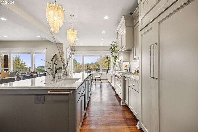 kitchen featuring gray cabinetry, light stone counters, hanging light fixtures, sink, and a chandelier