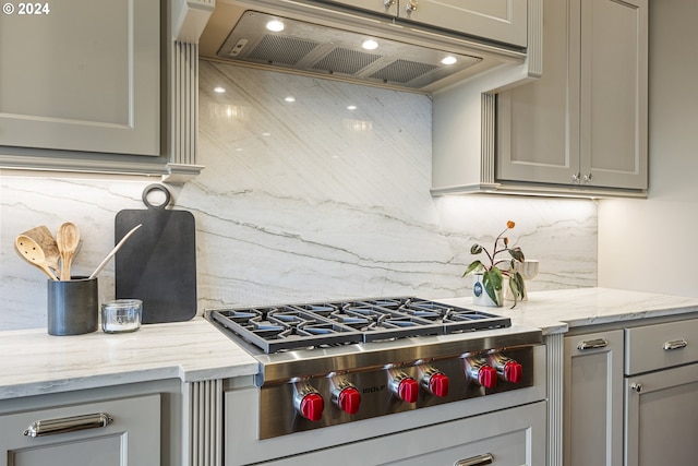 kitchen with gray cabinets, stainless steel gas stovetop, and decorative backsplash