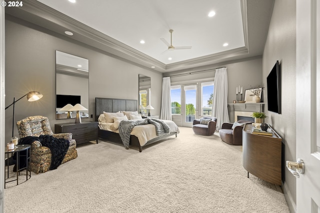 carpeted bedroom featuring ceiling fan, crown molding, and a tray ceiling