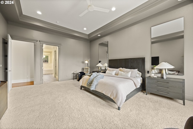 carpeted bedroom featuring ornamental molding, ensuite bath, ceiling fan, and a raised ceiling