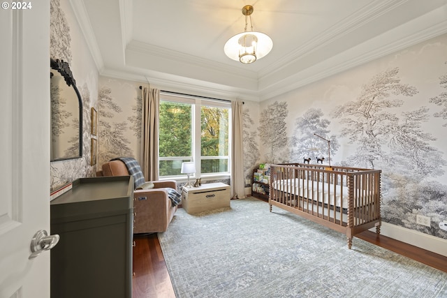 bedroom with dark hardwood / wood-style flooring, a chandelier, ornamental molding, and a crib