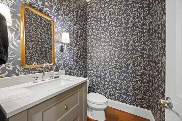 bathroom with toilet, vanity, and hardwood / wood-style flooring