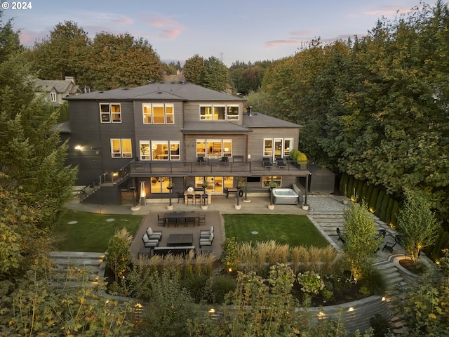 back house at dusk with a lawn, outdoor lounge area, and a patio