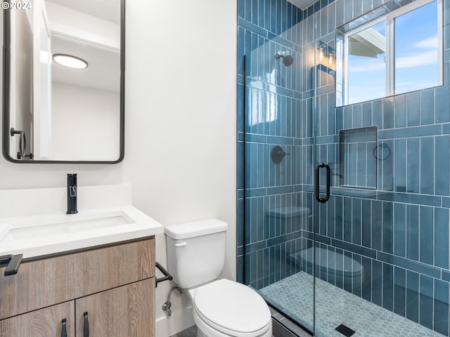 bathroom featuring toilet, vanity, and a shower with door