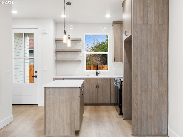 kitchen with sink, decorative light fixtures, a center island, light wood-type flooring, and electric stove