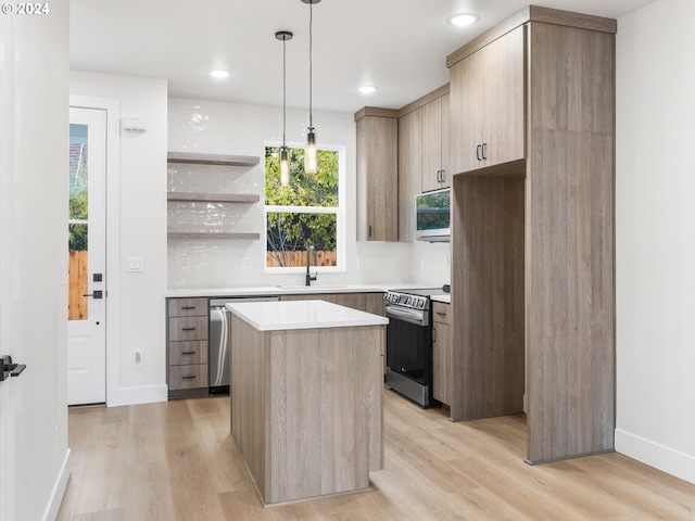 kitchen featuring appliances with stainless steel finishes, decorative light fixtures, a kitchen island, and light hardwood / wood-style flooring