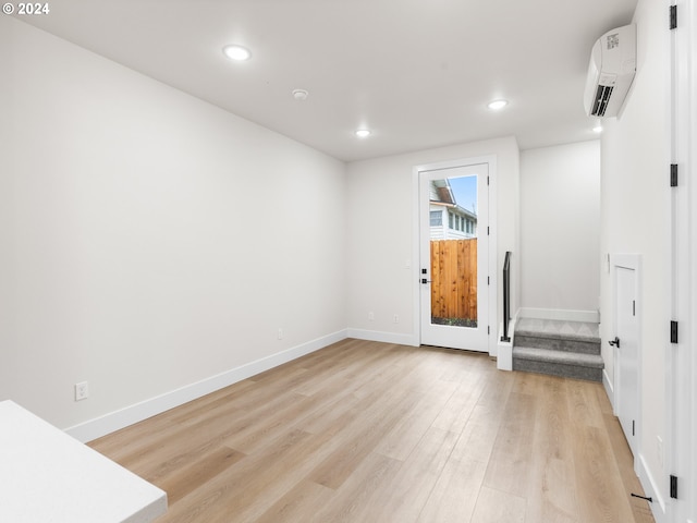 unfurnished room featuring light wood-type flooring and a wall mounted air conditioner