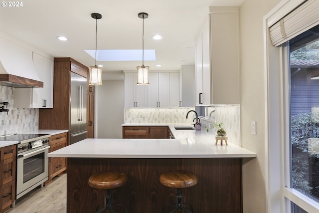 kitchen with decorative backsplash, sink, high quality appliances, white cabinets, and a breakfast bar area