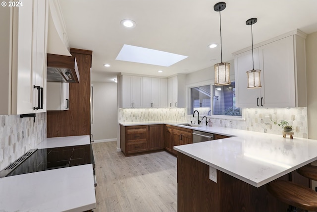 kitchen with light wood-type flooring, a skylight, custom range hood, sink, and white cabinets