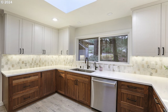 kitchen featuring decorative backsplash, light hardwood / wood-style floors, stainless steel dishwasher, and sink