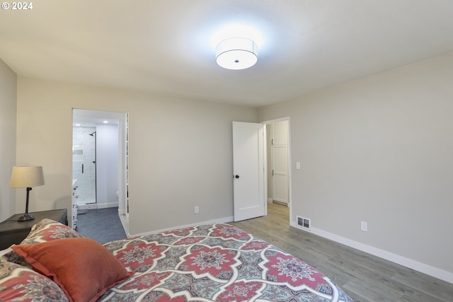 bedroom featuring connected bathroom and wood-type flooring