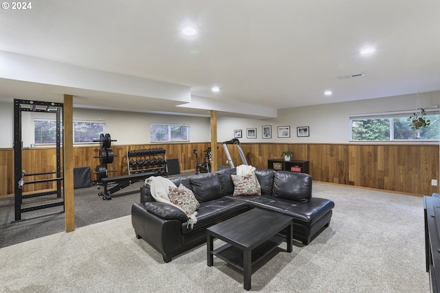 carpeted living room featuring wood walls