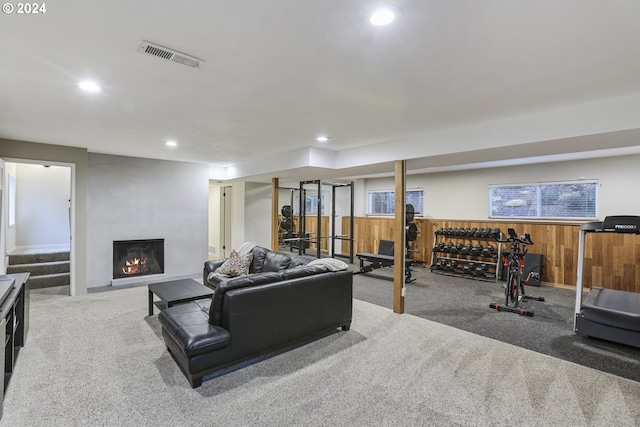 living room featuring wooden walls, a fireplace, and carpet