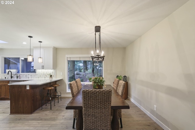 dining area with light hardwood / wood-style floors and an inviting chandelier