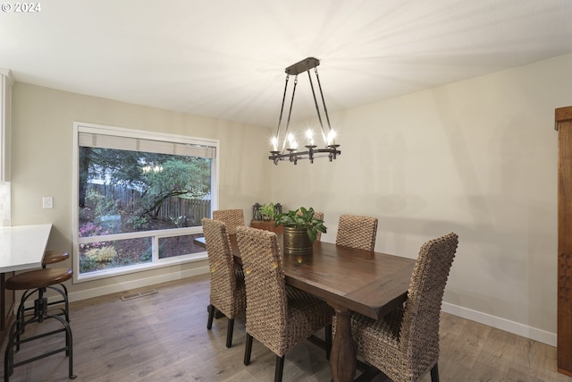 dining space with wood-type flooring and an inviting chandelier