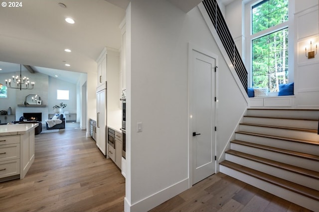 interior space featuring an inviting chandelier, wood-type flooring, and lofted ceiling