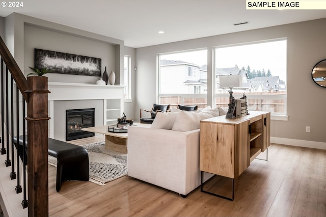 living room with a tile fireplace and light hardwood / wood-style flooring