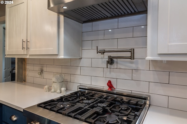 kitchen with extractor fan, decorative backsplash, white cabinets, and stainless steel gas stove