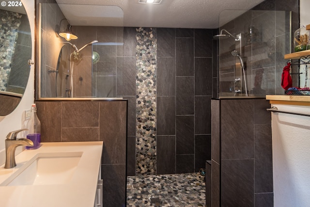 bathroom with a tile shower, a textured ceiling, and vanity