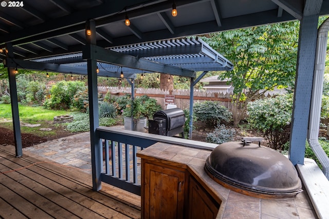 wooden deck with area for grilling and a pergola