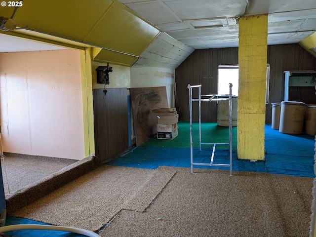 bonus room with lofted ceiling and wooden walls