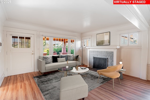 living room featuring plenty of natural light, ornamental molding, wood finished floors, and a tile fireplace