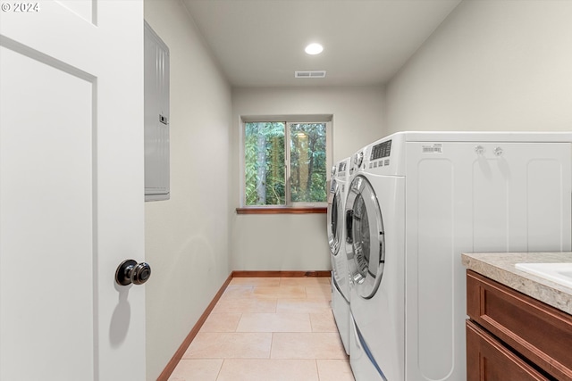 washroom featuring light tile patterned floors, washing machine and clothes dryer, and cabinets