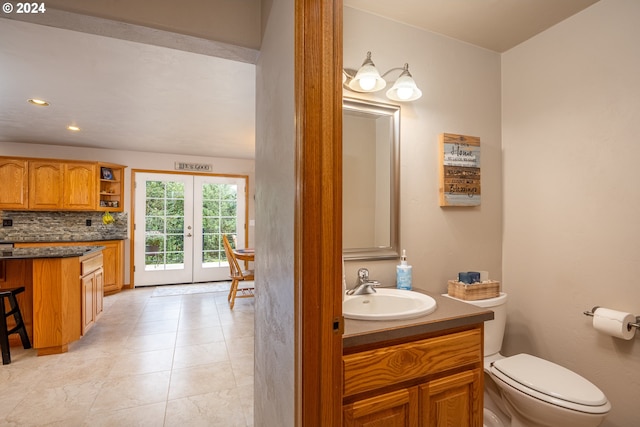 bathroom featuring backsplash, tile patterned floors, vanity, french doors, and toilet