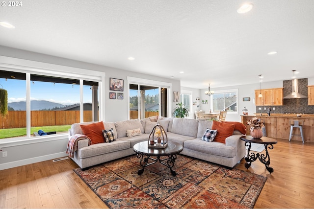 living room featuring a mountain view, a healthy amount of sunlight, wood-type flooring, and sink